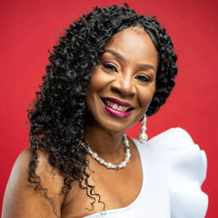 Woman with styled hair wearing a white dress against a red background